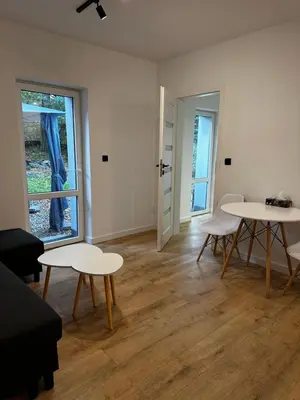 a room with two tables and chairs and a window at Nowoczesny apartament z ogrodem in Kraków