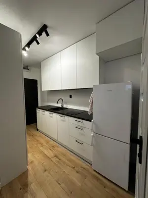 a kitchen with white cabinets and a white refrigerator at Nowoczesny apartament z ogrodem in Kraków