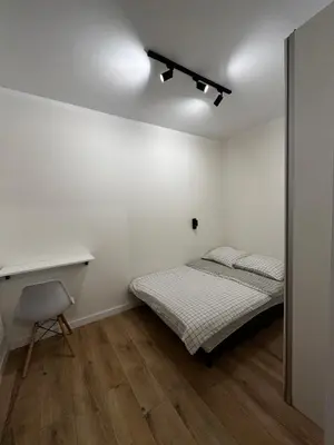 a white room with a bed and a desk at Nowoczesny apartament z ogrodem in Kraków