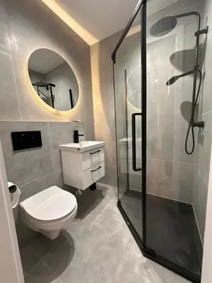a bathroom with a toilet and a shower and a mirror at Nowoczesny apartament z ogrodem in Kraków