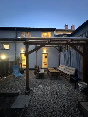 a backyard with a wooden pergola and a couch at Nowoczesny apartament z ogrodem in Kraków