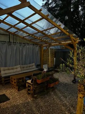 a patio with a wooden pergola and a couch at Nowoczesny apartament z ogrodem in Kraków