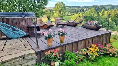 a wooden deck with flowers in flower pots on it at Pod Wysokim Niebem in Wysokie