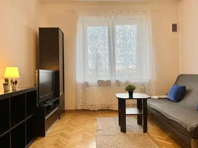 a living room with a couch and a tv and a window at City Center Apartment in Kraków