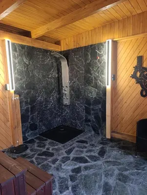 a room with a stone wall with a shower at Zawojskie Spanie in Zawoja