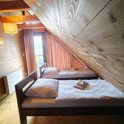 two beds in a room with a wooden wall at Beskidzkie Wyspy in Tenczyn