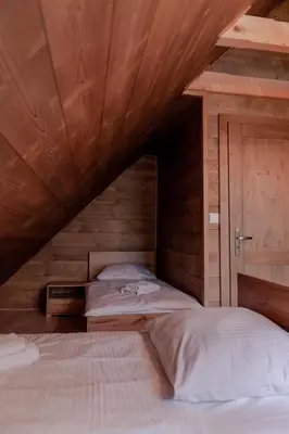 a bedroom with two beds in a wooden room at Beskidzkie Wyspy in Tenczyn