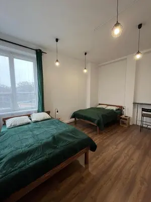 a bedroom with two green beds and a fireplace at W94 Hostel in Kraków