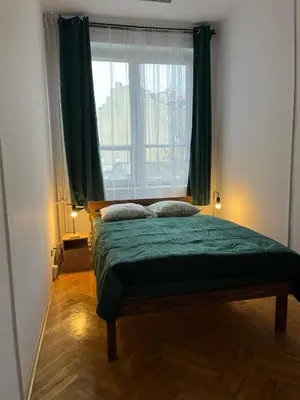 a bedroom with a green bed with a window at W94 Hostel in Kraków
