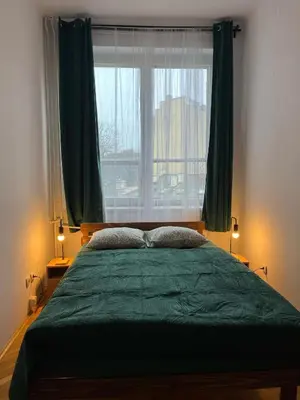 a bedroom with a large green bed with a window at W94 Hostel in Kraków