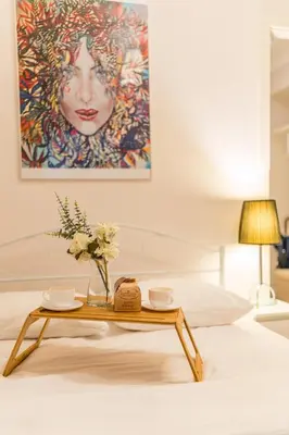 a table with flowers on a bed with a painting at Piasek Apt - Top Location, Patio, Tram&Bus nearby - by Rentujemy in Kraków