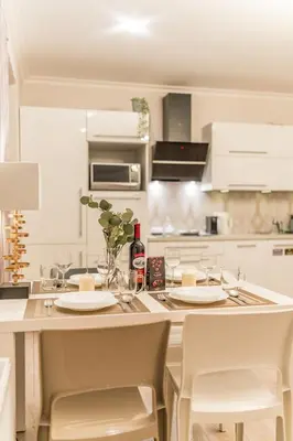 a white kitchen with a table with plates and chairs at Piasek Apt - Top Location, Patio, Tram&Bus nearby - by Rentujemy in Kraków