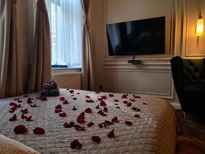 a bed with red rose petals on it at Apartament z Jacuzzi Kraków ART Koletek in Kraków