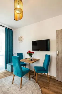 a dining room with a table and blue chairs at Apartamenty Astra in Oświęcim