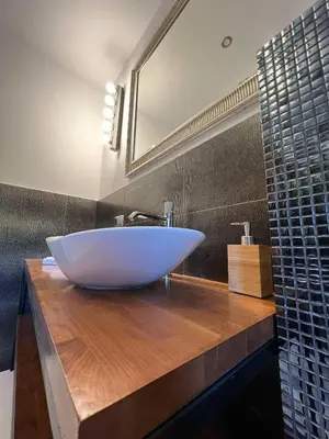 a bathroom with a large white sink on a wooden counter at Apartament Lumière in Oświęcim