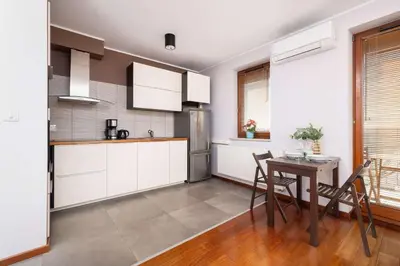 a kitchen with white cabinets and a table at Exceptional Apartment with Balcony by Noclegi Renters in Kraków