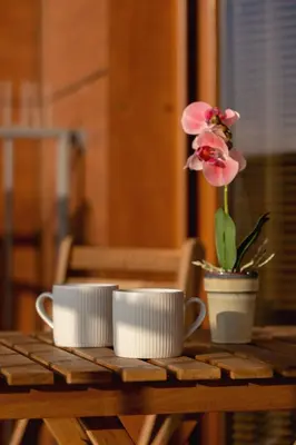 a table with two cups and a flower in a pot at Exceptional Apartment with Balcony by Noclegi Renters in Kraków