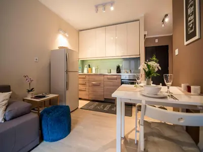 a kitchen with white cabinets and a table with chairs at Apartament Nad Wisłą in Kraków
