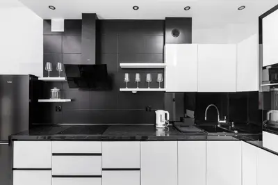 a black and white kitchen with white cabinets at Słowackiego 43 Apartament in Kraków