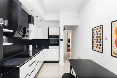 a kitchen with white cabinets and a black counter top at Słowackiego 43 Apartament in Kraków