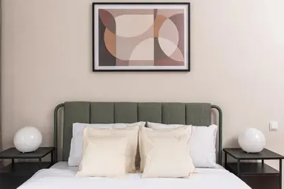 a bed with white pillows and a picture on the wall at Słowackiego 43 Apartament in Kraków
