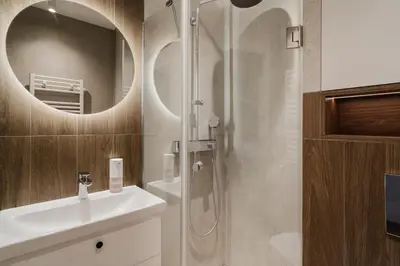 a bathroom with a shower and a sink and a mirror at Eleganckie Studio Royal w sercu Krakowa in Kraków