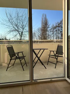 a patio with two chairs and a table through a window at Eleganckie Studio Royal w sercu Krakowa in Kraków