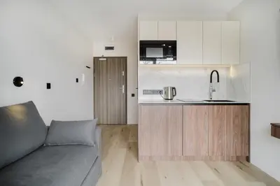 a living room with a couch and a kitchen at Eleganckie Studio Royal w sercu Krakowa in Kraków