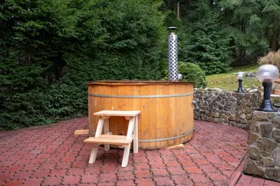 a wooden barrel with a stool next to a water fountain at Chata pod lasem z balią i sauną in Myślenice