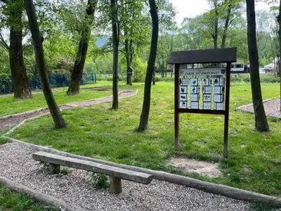 a park with a sign and a bench in the grass at Chata pod lasem z balią i sauną in Myślenice