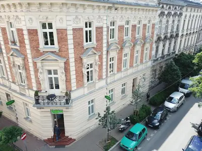 a large white building with cars parked in front of it at Apartamenty Czapskich in Kraków
