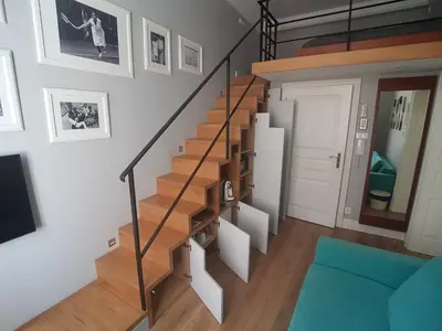 a spiral staircase in a living room with a blue couch at Apartamenty Czapskich in Kraków