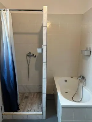 a bathroom with a shower with a tub and a bath tub at New KiKo in Kraków