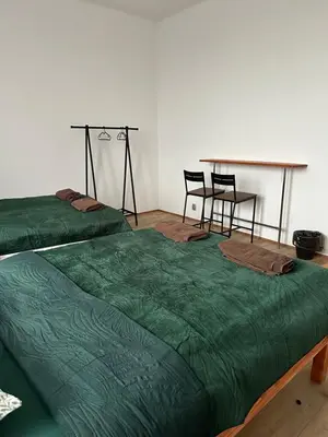 two green beds in a room with a table and chairs at New KiKo in Kraków