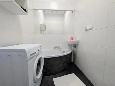 a white bathroom with a washing machine and a bath tub at Dąbrowskiego 15 by Homeprime in Kraków
