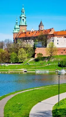 a building with a clock tower next to a body of water at Apartment in the Heart of Krakow - Between the Old Town and Kazimierz District in Kraków