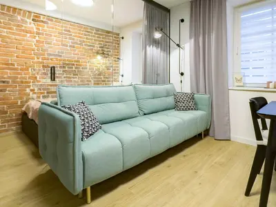 a blue couch in a living room with a brick wall at Dozen Kittens Apartment in Kraków