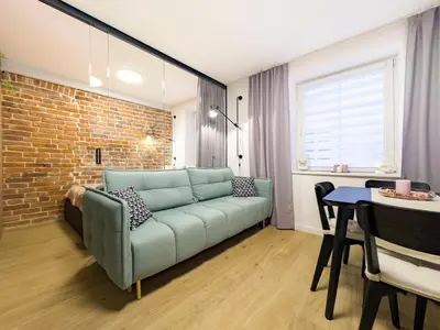 a living room with a couch and a brick wall at Dozen Kittens Apartment in Kraków