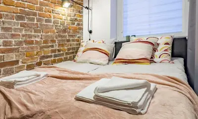 a large bed with pillows and a brick wall at Dozen Kittens Apartment in Kraków