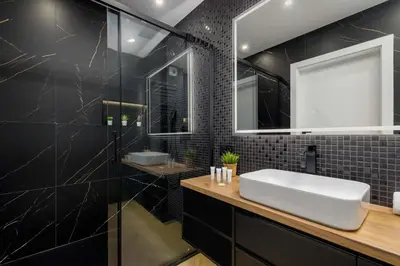 a bathroom with a white sink and black tiles at Luksusowy, Klimatyzowany Apartament w Krakowie z Biurkiem i Parkingiem by Renters Prestige in Kraków