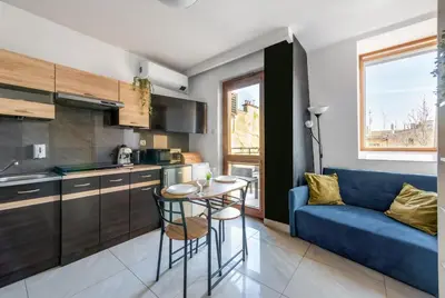 a kitchen and living room with a blue couch and a table at Charming Apartment with Air Conditioning for couples in the city center in Kraków