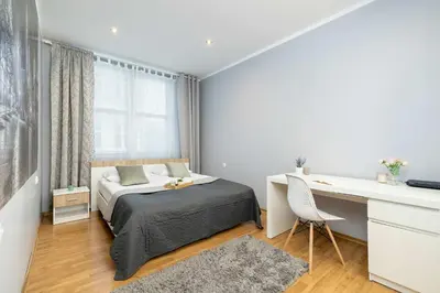 a bedroom with a bed and a desk and a desk at Bright Apartment Near Old Town and Wawel by Noclegi Renters in Kraków