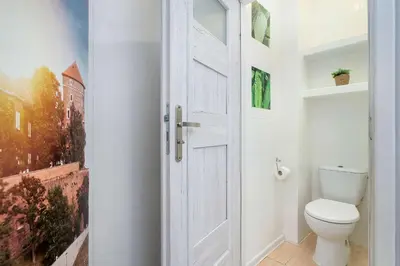 a bathroom with a white toilet and a door at Bright Apartment Near Old Town and Wawel by Noclegi Renters in Kraków