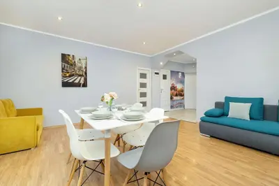 a dining room with a table and chairs and a couch at Bright Apartment Near Old Town and Wawel by Noclegi Renters in Kraków