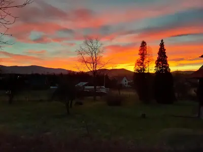 a sunset in a field with trees and mountains at Willa Świt in Maków Podhalański