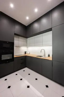 a kitchen with black cabinets and a white tile floor at Native Apartments Rajska 6 in Kraków