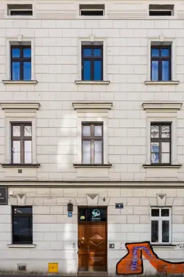 a white brick building with a brown door and windows at Native Apartments Rajska 6 in Kraków