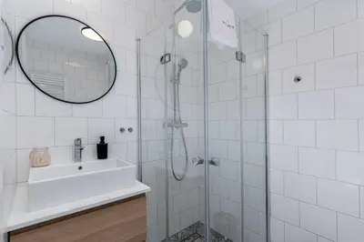 a bathroom with a shower with a sink and a mirror at inQse Krakow Centre in Kraków