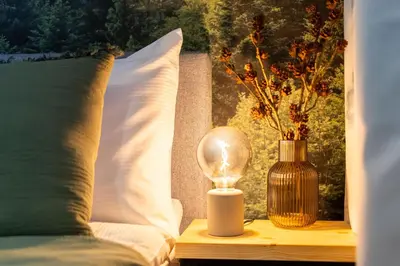 a lamp and a vase on a table next to a bed at Forest House by Cozyplace in Kraków