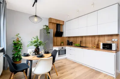 a kitchen with white cabinets and a table and chairs at Forest House by Cozyplace in Kraków